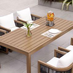 an outdoor dining table with white cushions on it