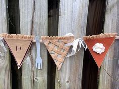 a wooden fence with three pieces of pie hanging from it's sides and two forks on each side