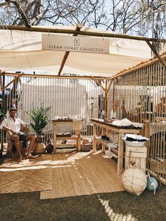 a man sitting on a bench in front of a wooden structure with white awnings