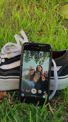 a cell phone sitting on top of a pair of shoes in the grass next to a shoelace