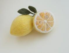 an orange cut in half sitting next to a piece of fruit on a white surface