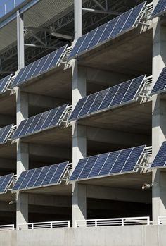 solar panels on the side of a building with balconies and railings around them