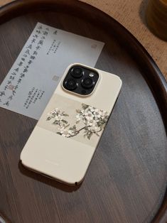 an iphone case sitting on top of a table next to a piece of paper with flowers