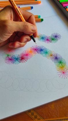 someone is doing something with colored pencils on the paper and they are drawing fireworks