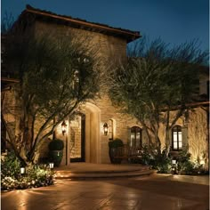 a house lit up at night with trees and bushes