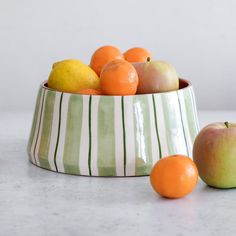 a bowl filled with oranges and apples on top of a counter next to two lemons