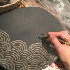 a person is using a brush to paint the design on a plate