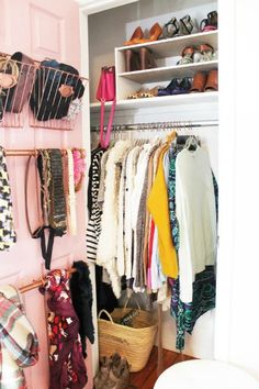 a closet filled with clothes and shoes next to a white toilet in a room that has pink walls