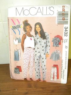 two women in pajamas standing next to each other on a wooden table with the cover over them