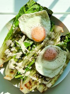 two fried eggs on top of lettuce in a white bowl