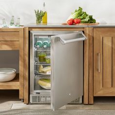 an open refrigerator in a kitchen with food on the counter and vegetables sitting inside it