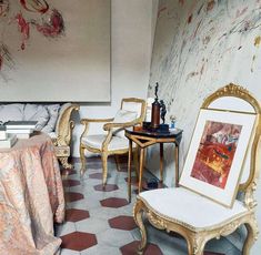 a room with chairs and paintings on the wall