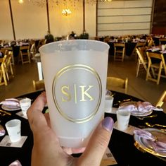 a person holding up a frosted cup in front of tables with gold trimmings