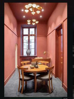 a dining room with red walls and wooden table surrounded by chairs in front of a window