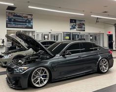 two cars parked in a showroom with their hood open