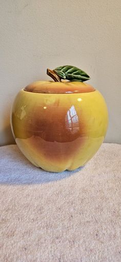 a yellow vase sitting on top of a carpeted floor next to a white wall