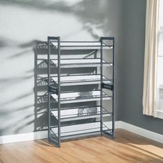 a metal shelf with several magazines on it in front of a gray wall and wooden floor