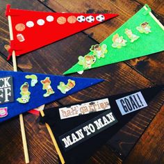 four pennants with stickers on them sitting on top of a wooden table next to each other