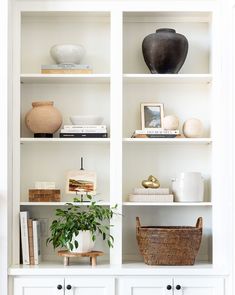 a white bookcase with books and vases on it