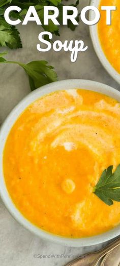 two white bowls filled with carrot soup and garnished with parsley