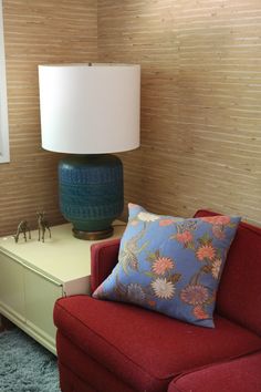 a living room with a red couch and a blue vase on the table next to it