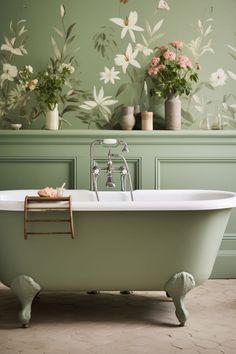 an old fashioned bathtub with flowers on the wall and green painted walls behind it