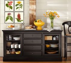 a black buffet table with plates and bowls on it in a room that has white walls