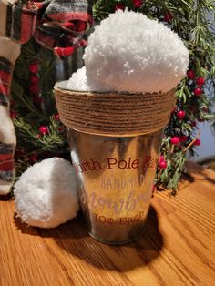 a bucket filled with snow sitting on top of a wooden table next to a christmas tree