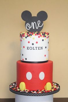 a three tiered cake decorated with mickey mouse ears and polka dot decorations on top