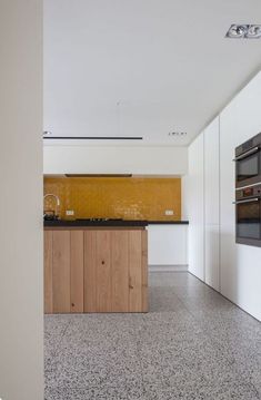 an empty kitchen with white cabinets and black counter tops