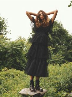 a woman standing on top of a rock with her hands behind her head