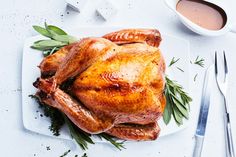 a roasted turkey on a white platter with herbs