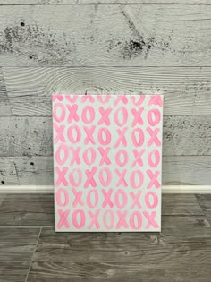 pink and white xoxo pattern on canvas against wooden wall with wood flooring