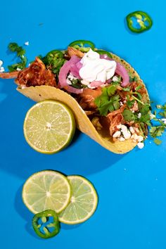 a taco filled with meat, onions and cilantro on a blue surface