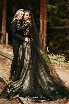 two people standing next to each other in the woods wearing black and gold wedding dresses