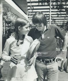 a man and woman standing next to each other in front of a building holding hats