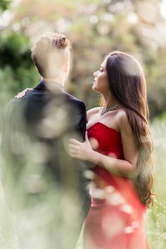 a woman in a red dress standing next to a man