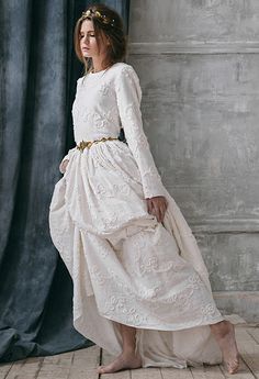 a woman in a white dress is standing near a curtain