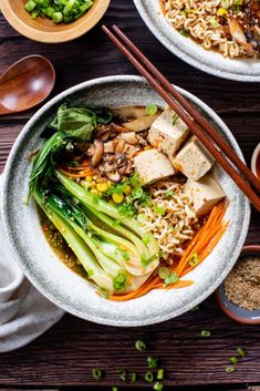 two bowls filled with food and chopsticks on top of a wooden table next to rice