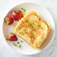 a white plate topped with two pieces of toast and strawberries on top of it