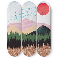 three snowboards with trees, mountains and birds painted on them