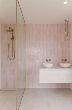 a bathroom with two sinks and a shower in the corner, pink tiles on the wall