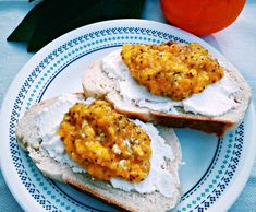 two pieces of bread on a plate with cream cheese and an orange in the background