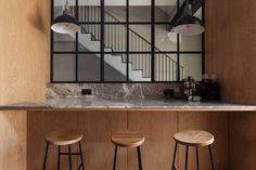 three stools in front of a counter with a mirror on the wall above it