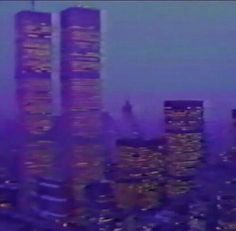 an aerial view of two skyscrapers in the middle of a city at night time