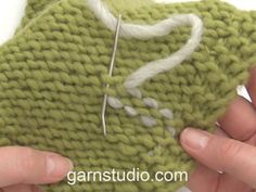 two hands are stitching together a piece of green knitted material with white thread