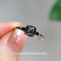 a hand holding a tiny black diamond ring