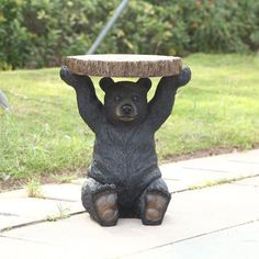 a black bear statue sitting on its hind legs holding a piece of wood over it's head