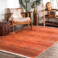 an orange rug in a living room next to a chair and table with vases on it