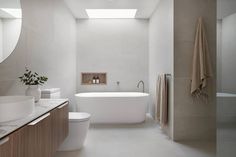 a bathroom with a white bath tub sitting next to a sink under a large mirror